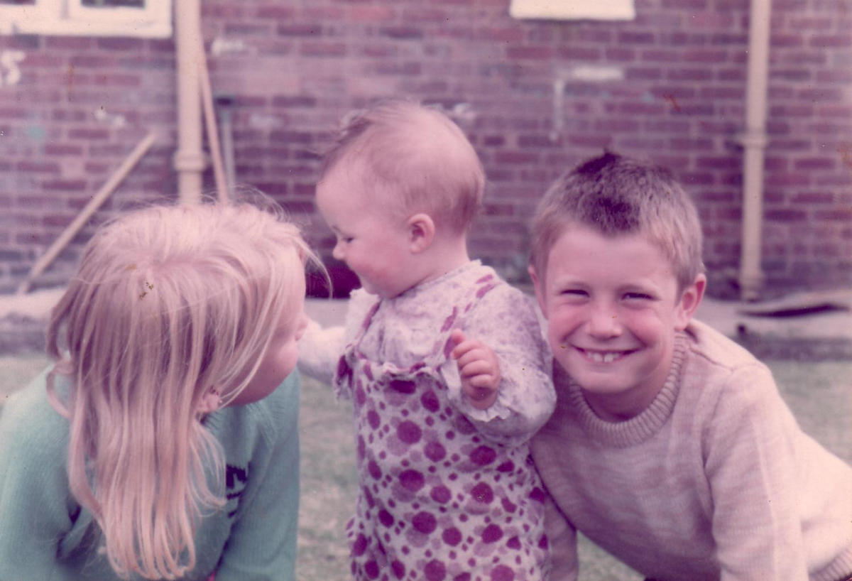 The same mid-1970s family photograph before restoration, faded and soft